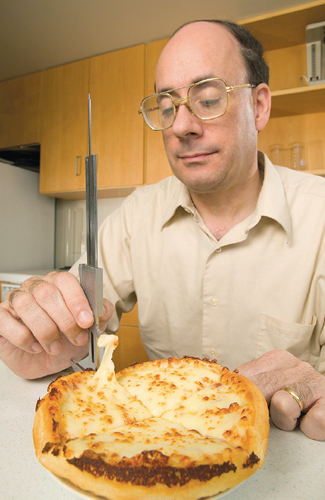 Author Michael H. Tunick, a research chemist specializing in dairy products, measures the stretchiness of low-fat mozzarella on a take-out pizza. <strong>From <em>The Science of Cheese</em>.<strong>