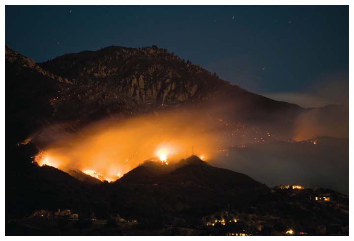 Almost 300 homes were lost during a 2008–2009 series of wildfires in the hills of the Santa Barbara region of California, including the May 2009 Jesusita wildfire, shown here burning in the foothills above Santa Barbara on its first night, ultimately incurring a cost of $20 million. As climate change alters temperature and precipitation regimes, wildfires in some regions are becoming more likely. Despite ample research informing ways to plan for fire and prevent damages, pervasive misunderstandings hinder better policy. <strong>Cody Duncan/Alamy Stock Photo</strong>